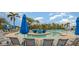 Beautiful community pool with comfortable lounge chairs, umbrellas, and lush tropical landscaping at 8403 Grand Estuary Trl # 204, Bradenton, FL 34212
