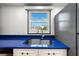 Modern kitchen sink with blue countertops, white cabinets, and a window view of the cityscape at 105 4Th Ne Ave # 405, St Petersburg, FL 33701
