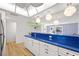 Open-concept kitchen featuring white cabinets, blue countertops, modern lighting, and stainless steel appliances at 105 4Th Ne Ave # 405, St Petersburg, FL 33701
