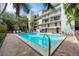 Community outdoor pool surrounded by tall palms, balconies, lounge chairs, and community building at 105 4Th Ne Ave # 405, St Petersburg, FL 33701