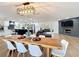 Open-concept area featuring hardwood floors, a modern light fixture, and a large wooden dining table at 11335 Mcmullen Loop, Riverview, FL 33569