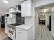 Modern kitchen with stainless steel range, white cabinetry, and adjacent laundry area with patterned floors at 11335 Mcmullen Loop, Riverview, FL 33569