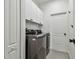 Modern laundry room with new stainless steel washer and dryer, white cabinets, and tile flooring at 12037 Mountbatten Dr, Tampa, FL 33626