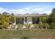 Charming rear exterior patio with sliding glass doors and lush landscaping offers a private outdoor retreat at 1484 Gladys Cir, Dunedin, FL 34698