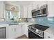 Updated kitchen showcasing white cabinets, stainless steel appliances, and a stylish blue backsplash at 16125 4Th E St, Redington Beach, FL 33708