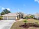 Inviting home with a well-manicured lawn, a large driveway leading to a three-car garage, and lovely palm tree accents at 182 Rotonda N Blvd, Rotonda West, FL 33947