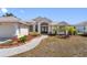 Inviting single-story home showcasing a well-manicured lawn, palm trees, and a charming walkway leading to a double door entrance at 182 Rotonda N Blvd, Rotonda West, FL 33947