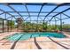 Enclosed pool featuring a unique shape, privacy landscaping and a stone patio at 182 Rotonda N Blvd, Rotonda West, FL 33947