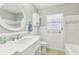 Well-lit bathroom with a large mirror, white cabinetry, and tiled shower/bath at 1839 Ridgeway Dr, Clearwater, FL 33755