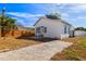 Exterior view of the home with a gravel driveway, fenced yard and blue skies at 2725 W Beach St, Tampa, FL 33607