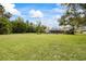 Large backyard featuring an expansive lawn, mature trees, and partial view of the house at 30 Stanton Cir, Oldsmar, FL 34677