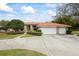 A home with a wide driveway, a three car garage, and a tile roof surrounded by lush landscaping at 30 Stanton Cir, Oldsmar, FL 34677