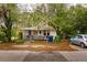 Charming single-story home featuring a yellow front door, mature trees, and an unfenced front yard at 3425 E Powhatan Ave, Tampa, FL 33610