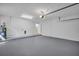 Spacious two car garage with gray painted floor, an entry door, and overhead storage at 375 Holly Hill Rd, Oldsmar, FL 34677