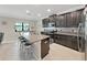 A modern kitchen featuring granite countertops, a central island with bar seating, and stainless steel appliances at 4136 Shrewbury Pl, Land O Lakes, FL 34638