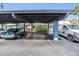 Covered carport parking area with two cars, landscaping, and a view of the building at 4215 Regal Pl, New Port Richey, FL 34652