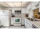 Well-lit kitchen featuring white appliances, cabinetry, tile flooring, and ample counter space at 4215 Regal Pl, New Port Richey, FL 34652