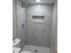Modern shower featuring gray marble-style tile and a herringbone patterned floor at 4731 Foothill Dr, Holiday, FL 34690