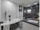 Modern bathroom features an elegant standalone tub, sleek fixtures, and chic marble-look and black tiled walls at 4814 Knights Loop, Plant City, FL 33565