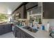 Outdoor kitchen featuring black cabinets, a sink, modern appliances, and decorative back splash at 4814 Knights Loop, Plant City, FL 33565
