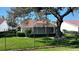 A back yard featuring an enclosed lanai with a tile roof and mature landscaping at 5839 Garden Lakes Dr, Bradenton, FL 34203