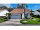 Charming single-story home with a lush green lawn, mature landscaping, a tile roof and a two-car garage at 5839 Garden Lakes Dr, Bradenton, FL 34203