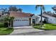 Charming single-story home features a two-car garage, brick driveway and tile roof amidst lush landscaping at 5839 Garden Lakes Dr, Bradenton, FL 34203