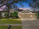 Charming single-story home featuring a three-car garage, lush landscaping, and a welcoming entrance at 6107 Ibispark Dr, Lithia, FL 33547