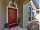 Inviting front entrance featuring a vibrant red door, decorative lighting, and elegant architectural details at 6107 Ibispark Dr, Lithia, FL 33547