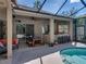 Covered outdoor patio area offers a dining space and outdoor bar overlooking a sparkling pool and lush landscaping at 6107 Ibispark Dr, Lithia, FL 33547