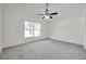 An airy bedroom features neutral carpet, a ceiling fan and large window at 7459 Oxford Garden Cir, Apollo Beach, FL 33572