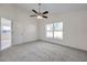 A well-lit bedroom with neutral carpet, ceiling fan, and bright window at 7459 Oxford Garden Cir, Apollo Beach, FL 33572