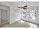 A bright bedroom features neutral carpet, ceiling fan, two windows and closet at 7459 Oxford Garden Cir, Apollo Beach, FL 33572