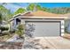 Charming home featuring a gray garage door, landscaped walkway, and a well-maintained exterior in a quiet neighborhood at 7459 Oxford Garden Cir, Apollo Beach, FL 33572