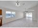 Bright living room features tile flooring, a ceiling fan, and natural light from the window and sliding glass doors at 7459 Oxford Garden Cir, Apollo Beach, FL 33572