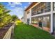 View of a house's backyard with a lush green lawn, a grill, and sliding glass doors leading to a patio at 7623 Radcliffe Cir # 112A, Port Richey, FL 34668