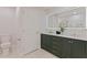 This bathroom showcases a green vanity with double sinks, a large, lighted mirror, and a toilet at 834 Riverside Dr, Tarpon Springs, FL 34689