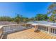 A sunny deck with wooden floors and white railing overlooking green trees beneath a bright blue sky at 834 Riverside Dr, Tarpon Springs, FL 34689