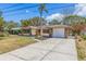 A well-maintained single-story home featuring a manicured lawn, mature landscaping, and a concrete driveway at 834 Riverside Dr, Tarpon Springs, FL 34689