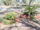A landscaped garden bed featuring various plants, mulch, and decorative stones surrounding a bird bath at 9377 Preston Rd, Brooksville, FL 34601