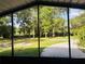 View from a screened porch to a grassy back yard with a concrete pad and mature trees beyond at 9377 Preston Rd, Brooksville, FL 34601