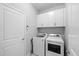 Clean laundry room featuring a full-size washer and dryer, upper storage cabinets, and tile floors at 12503 Candleberry Cir, Tampa, FL 33635