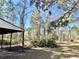 Lush backyard featuring mature trees and partial view of a carport at 13076 Kanawha Dr, Weeki Wachee, FL 34614