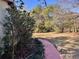 Large partially wooded backyard with pink concrete path on the side of the house at 13076 Kanawha Dr, Weeki Wachee, FL 34614