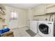 Functional laundry room with washer, dryer, shelving, and an exterior door at 1409 Castleworks Ln, Tarpon Springs, FL 34689