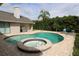 Backyard with a kidney-shaped pool, spa, barbecue grill, lounge chairs and lush landscaping at 16209 Belle Meade Blvd, Odessa, FL 33556