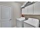 Bright laundry room with white washer and dryer and ample storage space above appliances at 16868 Scuba Crest St, Wimauma, FL 33598
