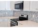 Modern kitchen range and backsplash, complemented by white cabinetry at 22442 Peachland Blvd, Port Charlotte, FL 33954