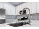 Close-up of kitchen sink featuring modern faucet, white countertops and tile backsplash at 22442 Peachland Blvd, Port Charlotte, FL 33954