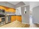 Modern kitchen with stainless steel appliances, wood cabinets, and a view into the living area at 2402 W Azeele St # 423, Tampa, FL 33609